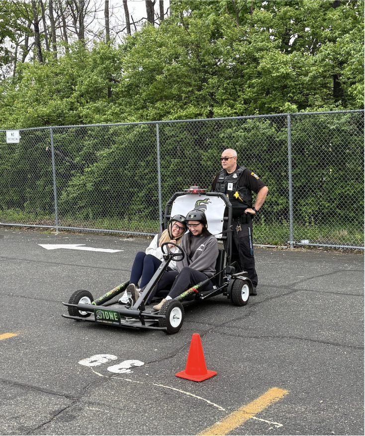 Seniors Emma Yakaitis and Kendra Morgan driving the SIDNE car, with Officer Nothstein supervising them.